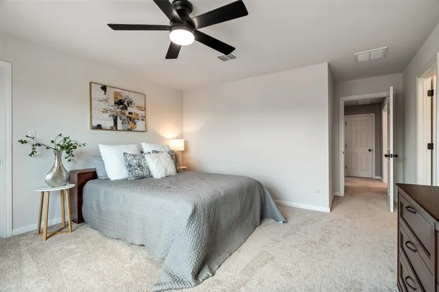a bedroom with a large bed and a chandelier fan