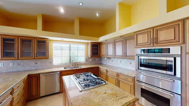 a kitchen with kitchen island a counter top space a sink stainless steel appliances and cabinets