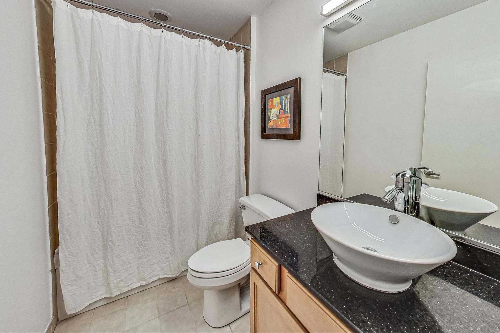 1111 West 14th Place, Unit 110 Chicago, IL 60608 - Photo 15 of 24 a white toilet sitting next to a bathroom sink