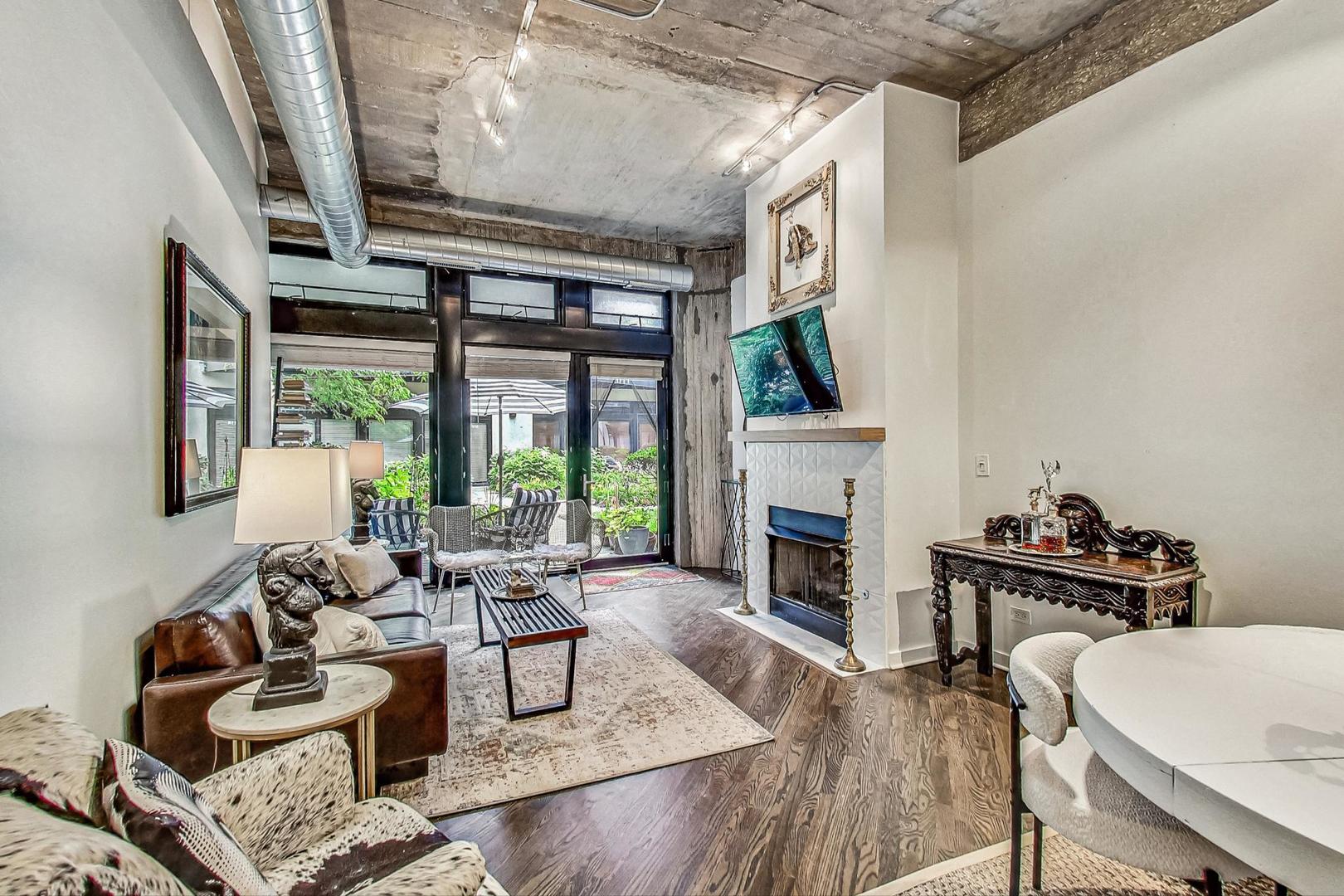 1111 West 14th Place, Unit 110 Chicago, IL 60608 - Photo 3 of 24 a living room with furniture a fireplace and a floor to ceiling window