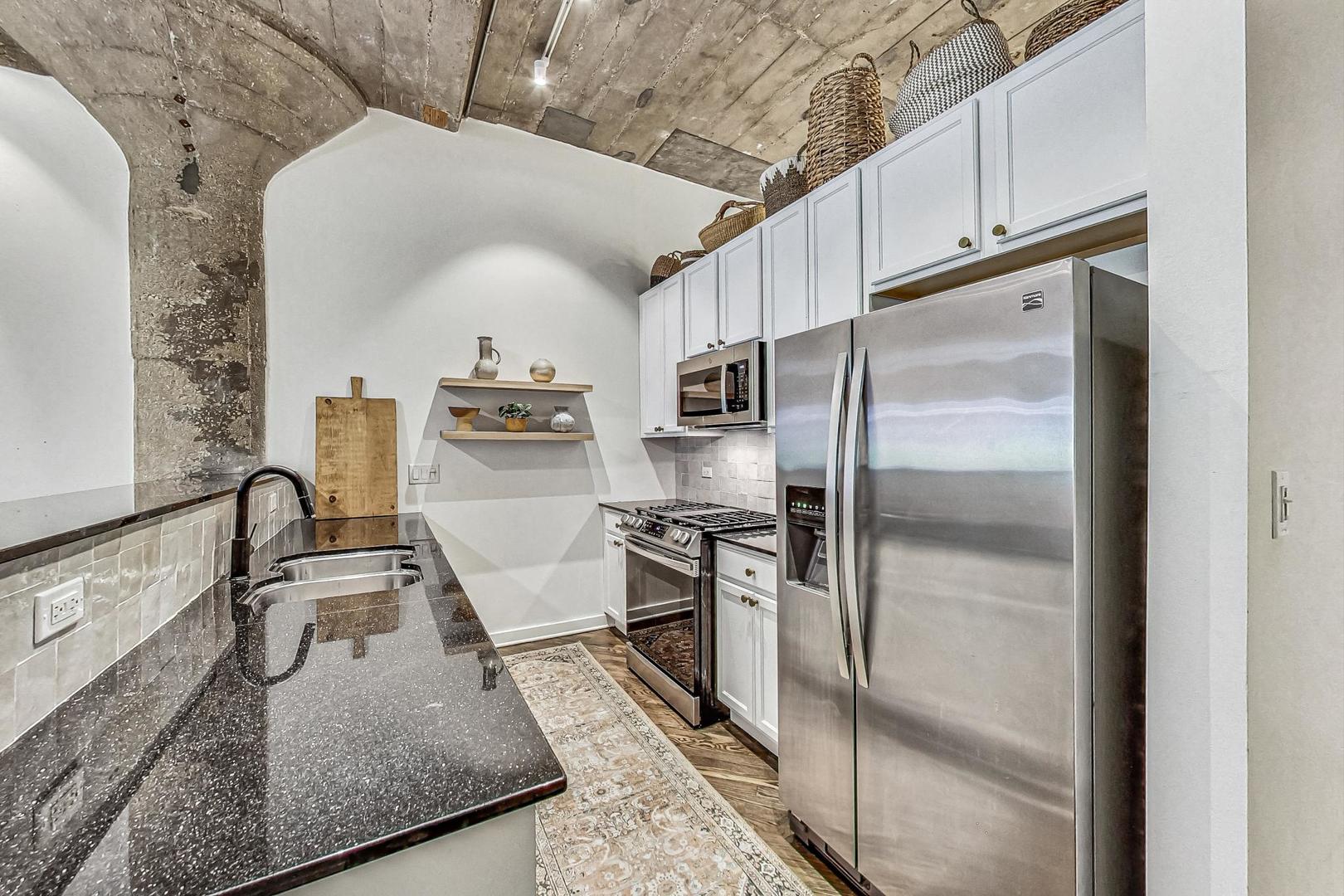 1111 West 14th Place, Unit 110 Chicago, IL 60608 - Photo 6 of 24 a kitchen with stainless steel appliances granite countertop a sink stove and refrigerator