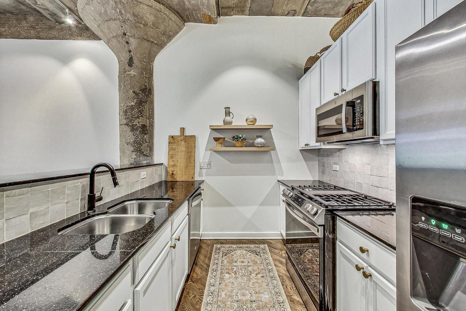 1111 West 14th Place, Unit 110 Chicago, IL 60608 - Photo 7 of 24 a kitchen with stainless steel appliances granite countertop a sink and cabinets