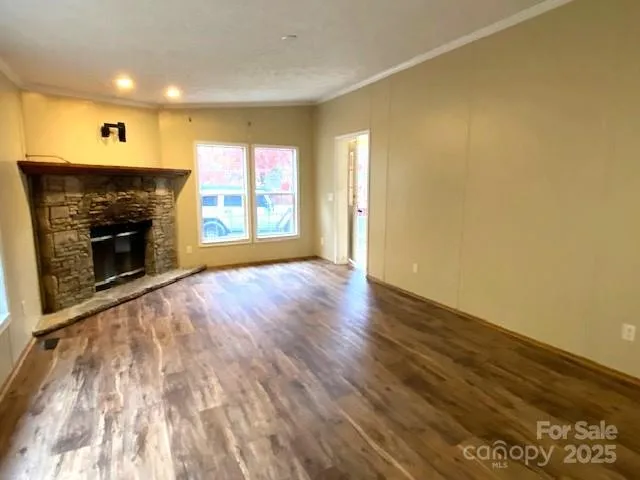 an empty room with wooden floor fireplace and windows