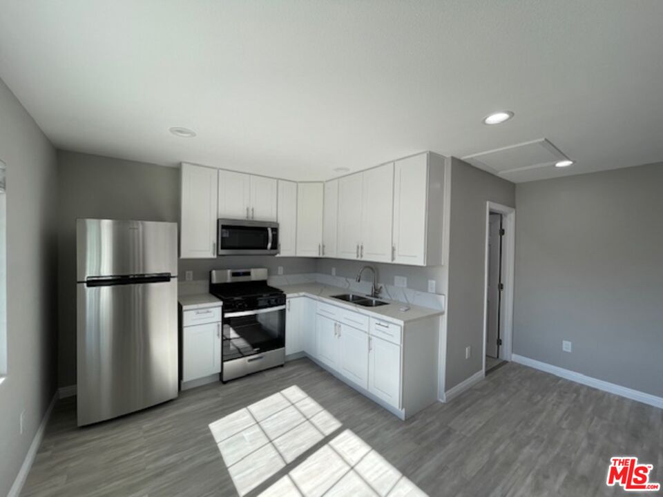 2615 Elizondo Avenue, Unit 2 Simi Valley, CA 93065 - Photo 8 of 20 a kitchen with a refrigerator a stove top oven and wooden floor