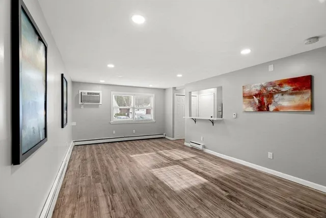 a view of an empty room with a window and wooden floor
