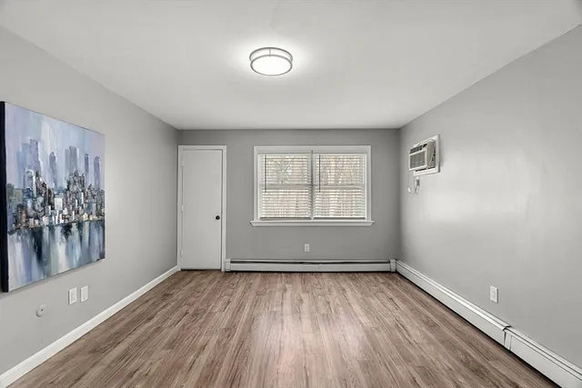 a view of an empty room with window and wooden floor