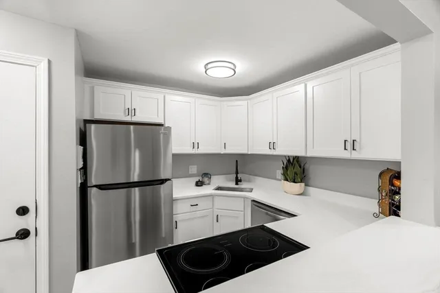 a kitchen with a refrigerator a stove and white cabinets