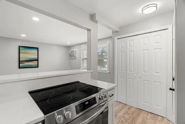 a large white kitchen with wooden floor and a refrigerator