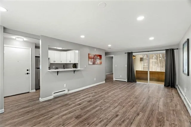 a view of an empty room with window and wooden floor