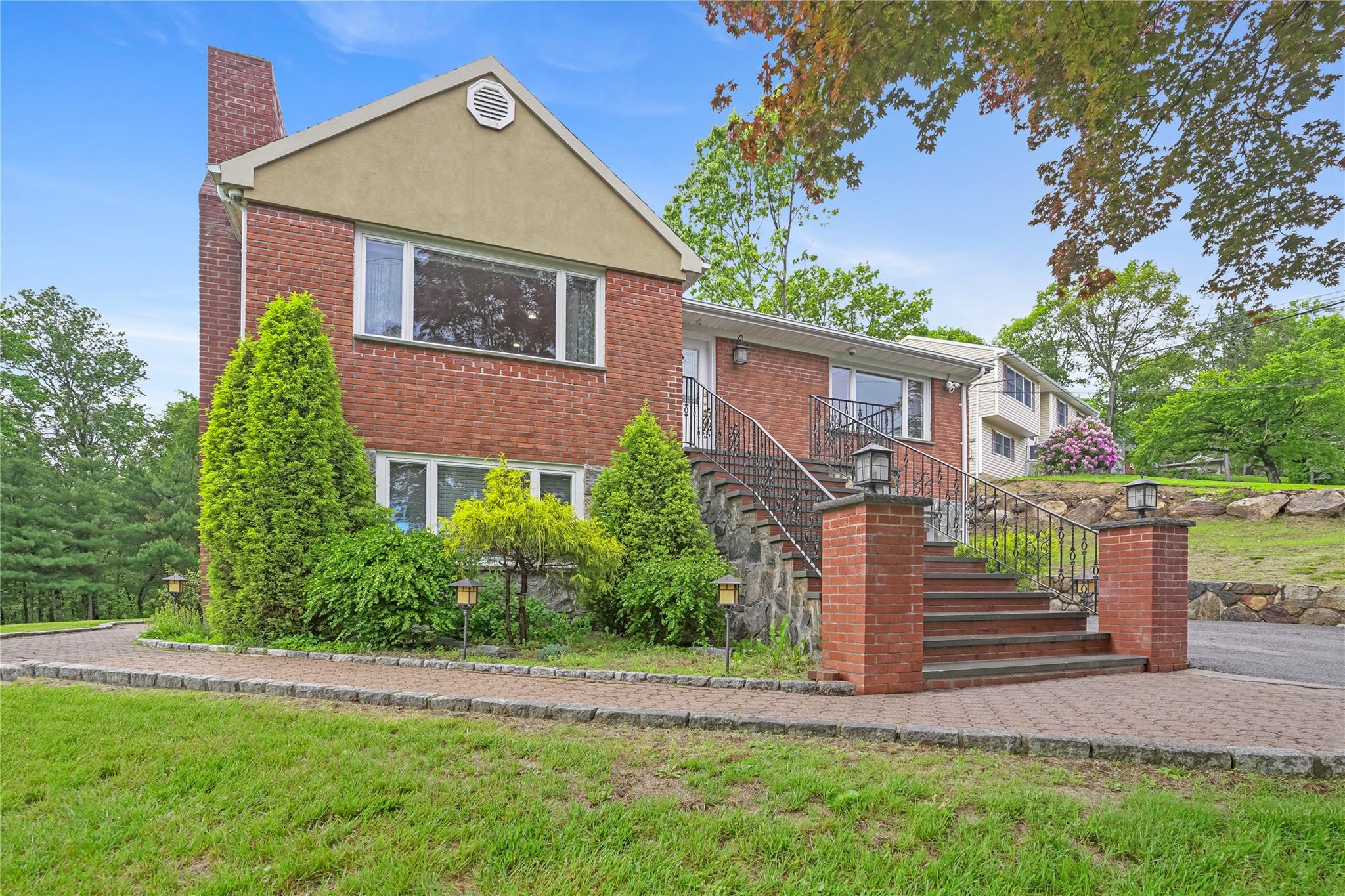 View of front of home with a chimney, stairs, and brick siding