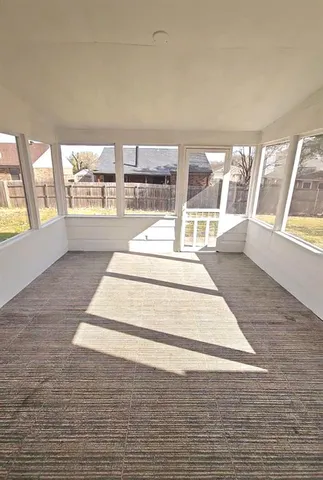 a view of an empty room with wooden floor and a fireplace
