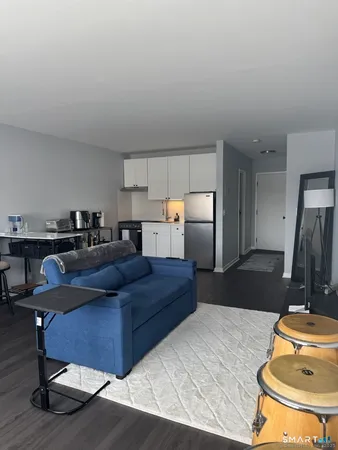 a living room with stainless steel appliances furniture a rug and a lamp