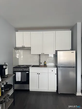 a kitchen with stainless steel appliances granite countertop a refrigerator a stove a sink and white cabinets