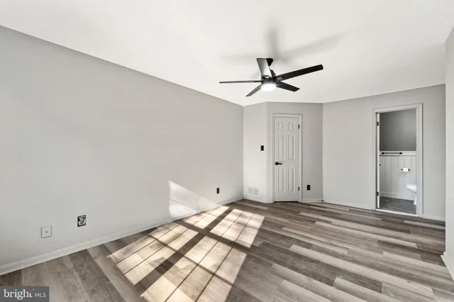a view of room with wooden floor and a ceiling fan