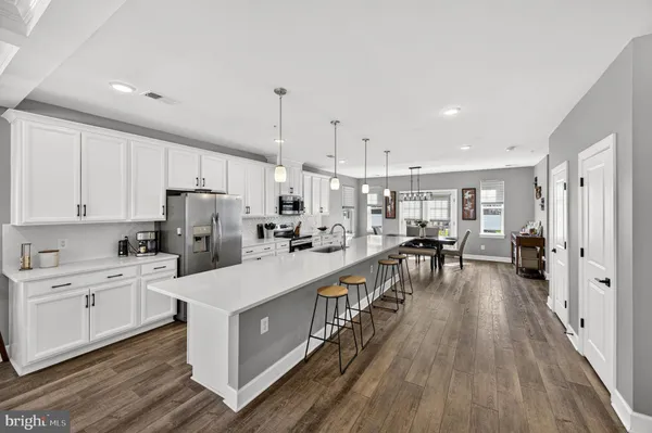 a large kitchen with kitchen island a refrigerator a stove a sink a center island and wooden floor