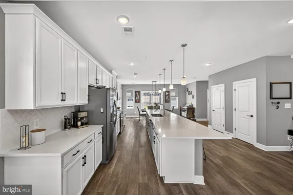 a kitchen with stainless steel appliances granite countertop a stove top oven a sink a dining table and chairs with wooden floor