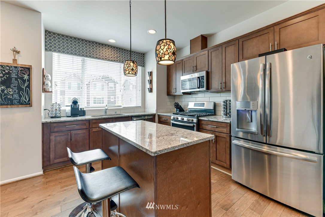 3337 30th Drive Everett, WA 98201 - Photo 17 of 28 a kitchen with granite countertop a refrigerator a stove a sink and a dining table with wooden floor