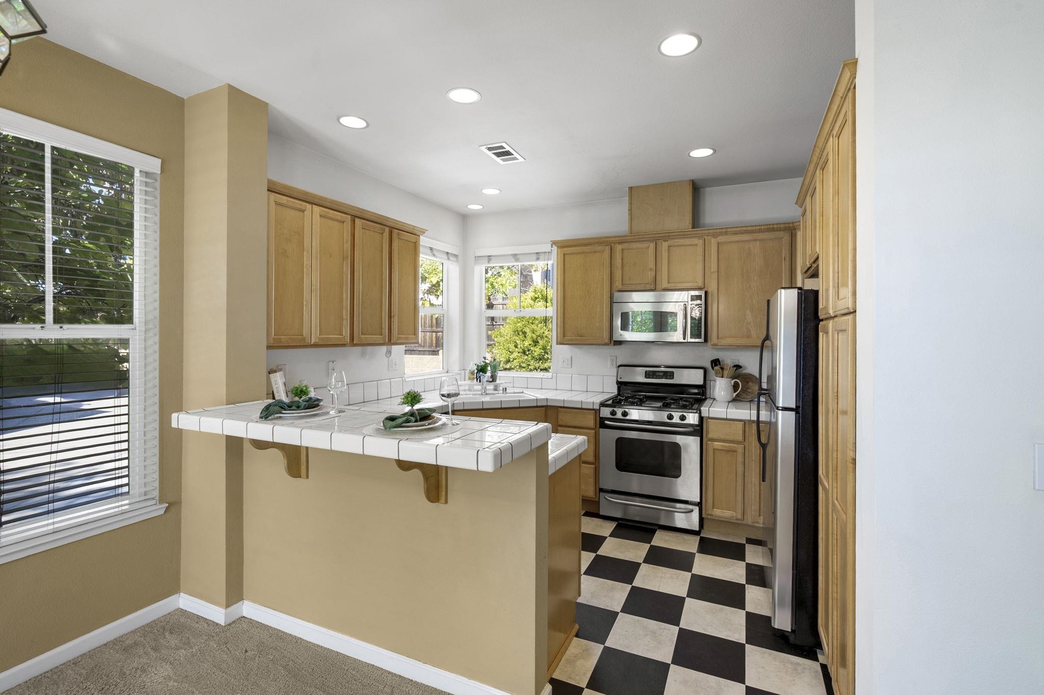 343 Field Stone Drive Murphys, CA 95247 - Photo 14 of 40 Kitchen featuring tile counters, light floors, stainless steel appliances, a breakfast bar, and a peninsula