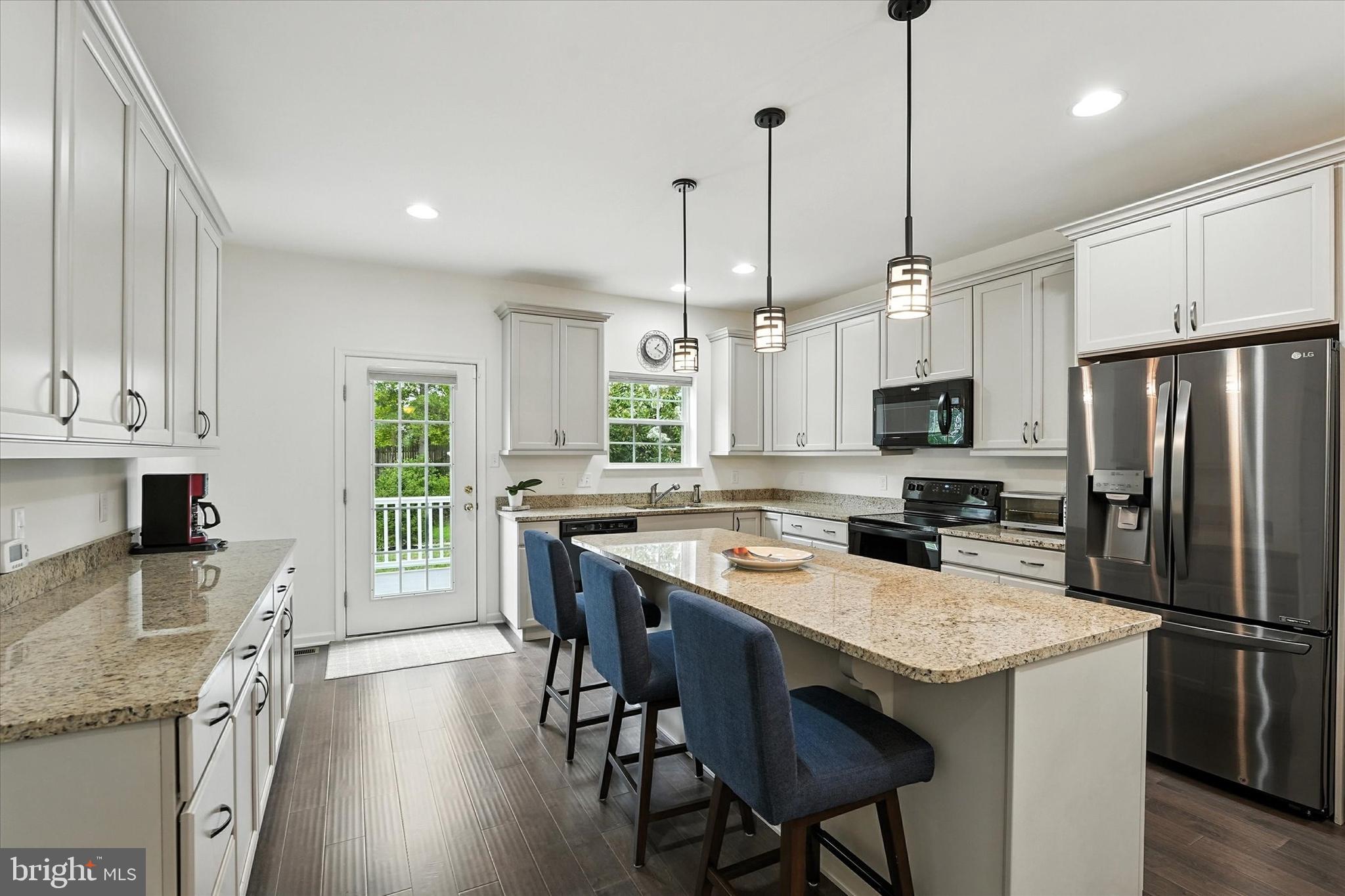 167 Sirius Drive Bear, DE 19701 - Photo 14 of 47 a kitchen with stainless steel appliances granite countertop a stove a refrigerator a kitchen island a sink cabinets and wooden floor