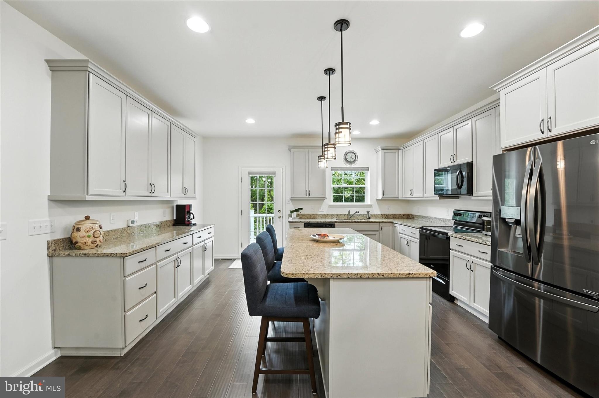167 Sirius Drive Bear, DE 19701 - Photo 15 of 47 a kitchen with stainless steel appliances kitchen island granite countertop a stove a sink a refrigerator and white cabinets with wooden floor