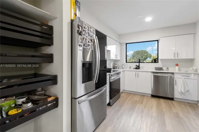 a kitchen with stainless steel appliances a sink and wooden floor