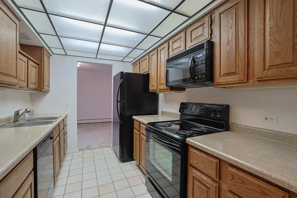 a kitchen with stainless steel appliances granite countertop a stove top oven a sink dishwasher and a refrigerator with wooden cabinets