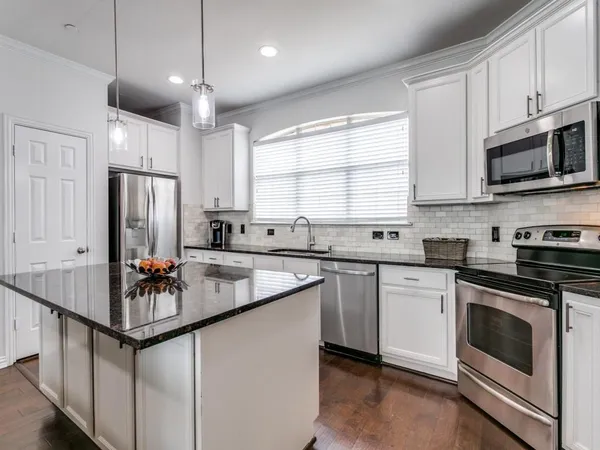 a kitchen with stainless steel appliances granite countertop a sink stove a refrigerator and microwave with wooden floor