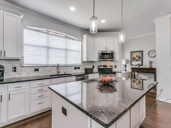 a kitchen with granite countertop stainless steel appliances a sink a counter space cabinets and a window