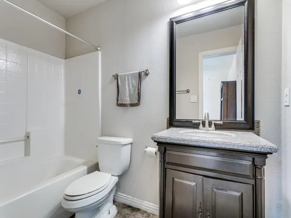 a bathroom with a granite countertop toilet sink and mirror