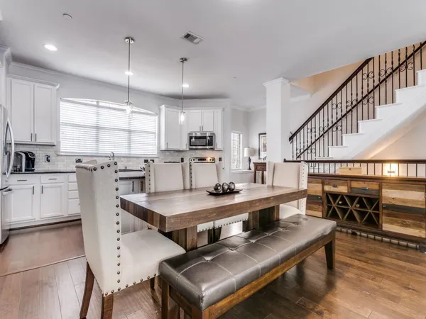 a living room with stainless steel appliances furniture a rug and a kitchen view