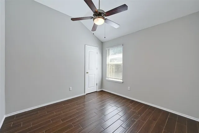 an empty room with wooden floor fan and windows