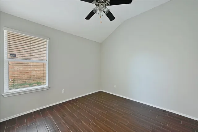 a view of a room with wooden floor a ceiling fan and windows