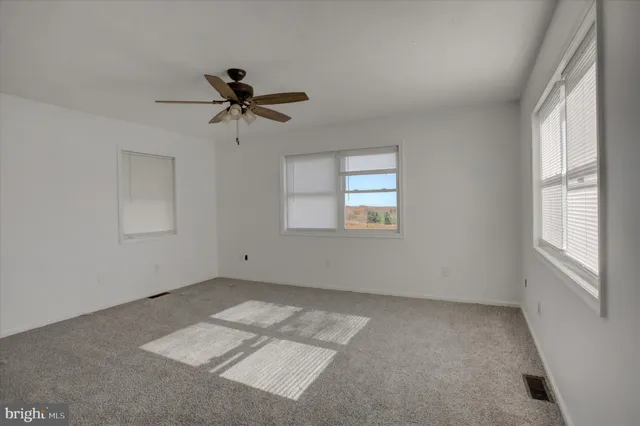 a view of a room that has a window and a ceiling fan
