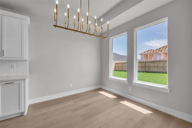 a view of an empty room with wooden floor and a ceiling fan