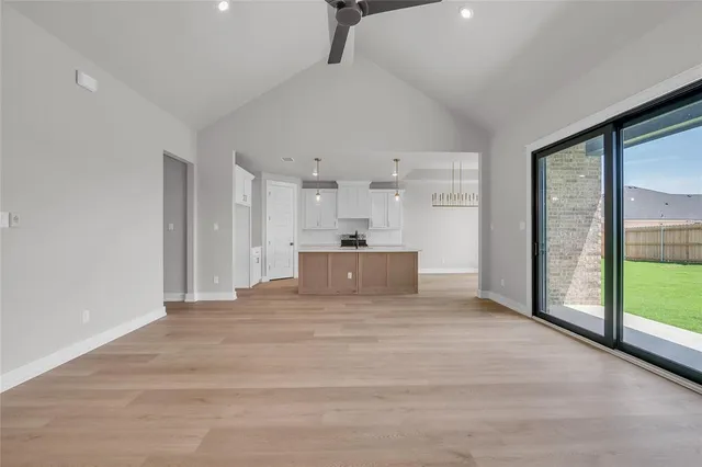 a view of an empty room with window and wooden floor