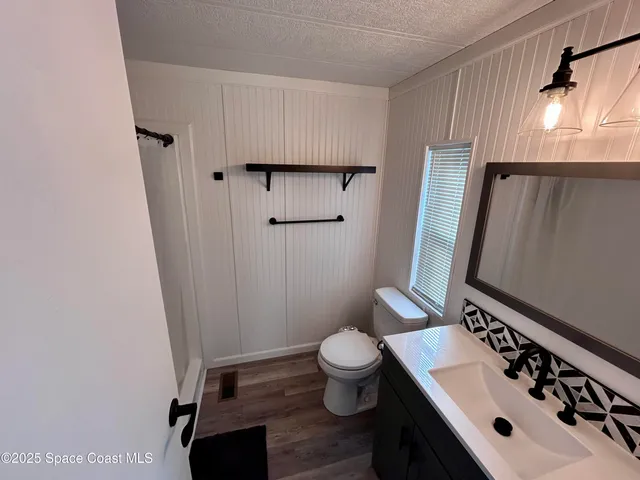 a bathroom with a sink a toilet a mirror and shower