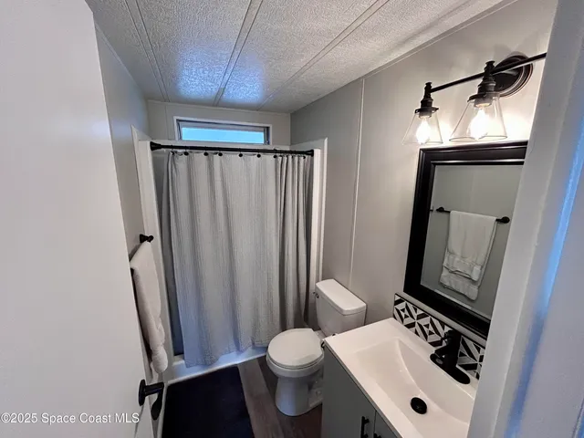 a bathroom with a sink a toilet a mirror and shower curtain