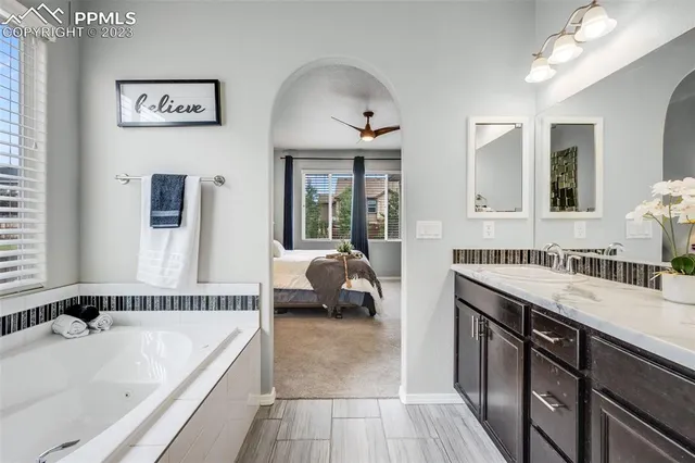a en suite spacious bathroom with a tub double vanity and window