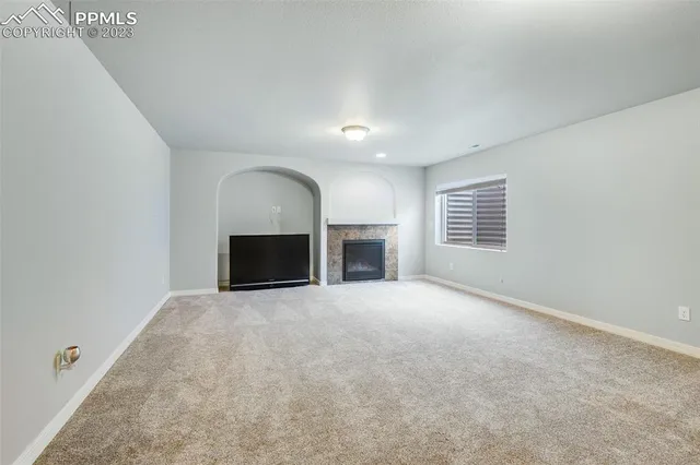 an empty room with fireplace and windows
