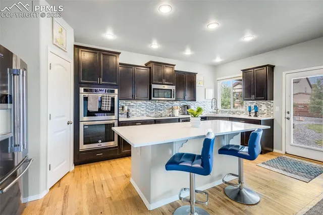 a large white kitchen with stainless steel appliances kitchen island granite countertop a refrigerator and a stove top oven