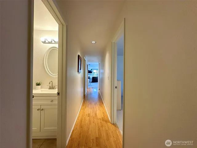 a view of a hallway with wooden floor and a bathroom