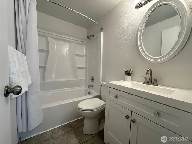a bathroom with a granite countertop toilet a sink and a mirror