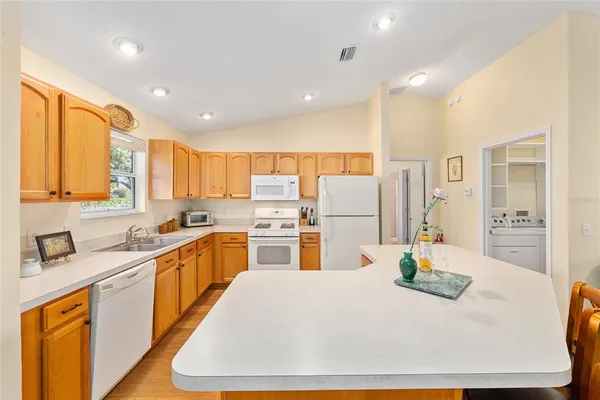 a kitchen with stainless steel appliances granite countertop a dining table chairs and a refrigerator