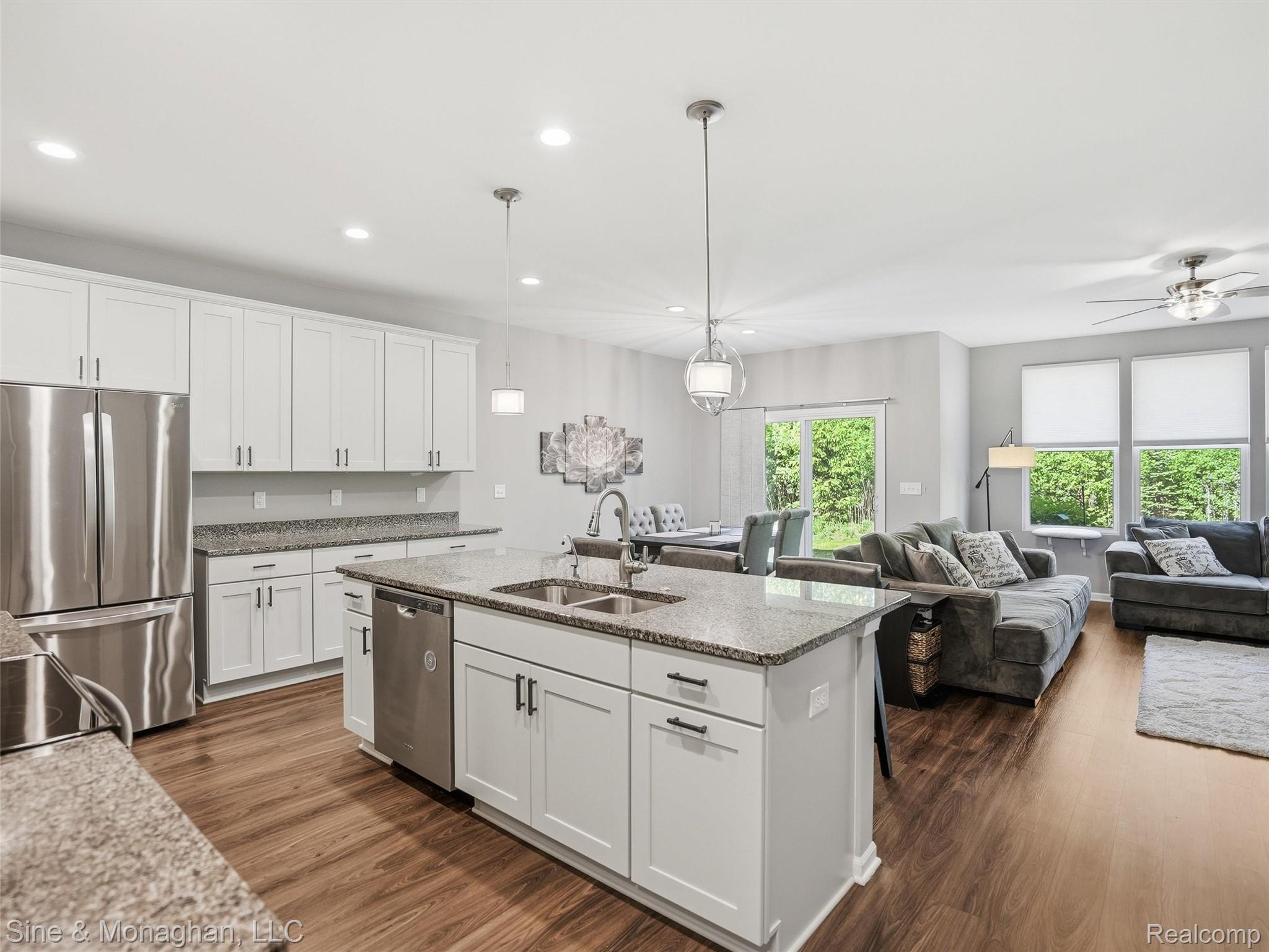 24827 Ivy Road Novi, MI 48375 - Photo 5 of 38 Modern kitchen featuring an island with double sinks, stainless steel appliances, white cabinetry, and wood-finish flooring