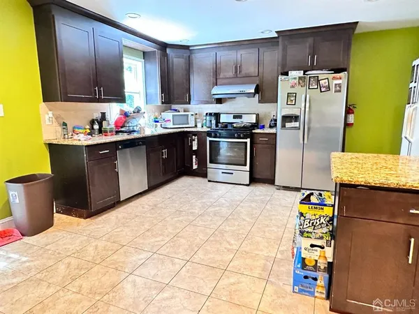 a kitchen with stainless steel appliances kitchen island granite countertop a refrigerator and a stove top oven