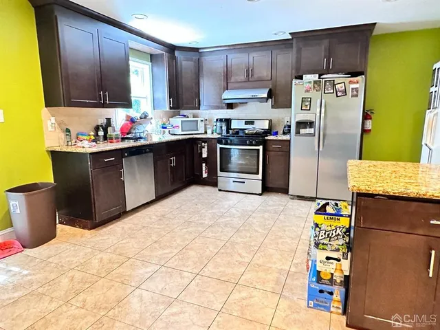 a kitchen with stainless steel appliances kitchen island granite countertop a refrigerator and a stove top oven