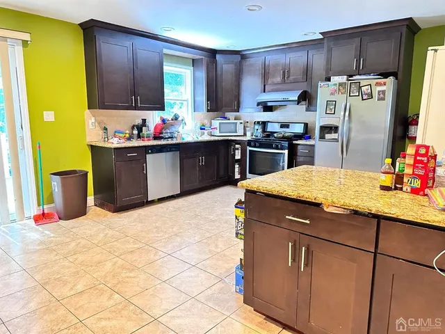 a kitchen with granite countertop a refrigerator a stove and a cabinets