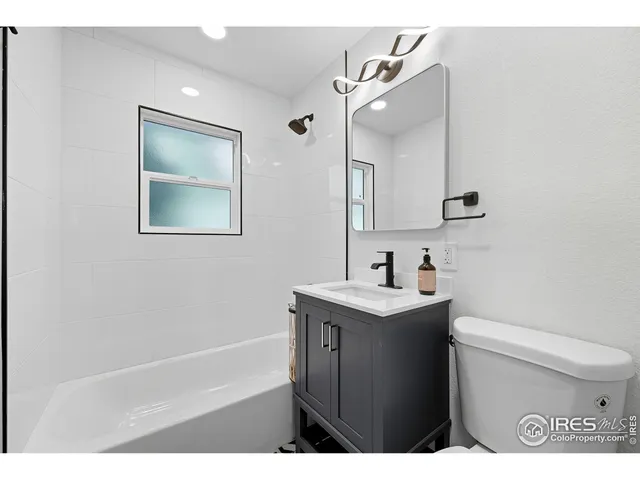 a bathroom with a granite countertop sink mirror vanity and toilet
