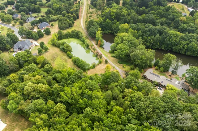 an aerial view of residential house with outdoor space and trees all around