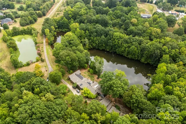 an aerial view of residential houses with outdoor space and trees all around